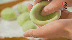 將均分的艾草面團(tuán)搓成圓，挖一個(gè)窩，放入餡心，再搓成圓。