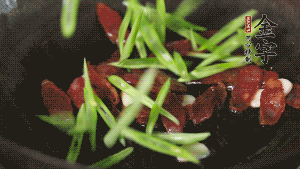 先后下香腸片、四季豆絲均勻翻炒，加適量清水燜煮一下。