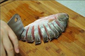 將鱸魚清洗干凈，從脊椎處切斷至腹部，腹部保留1cm左右不要切斷。