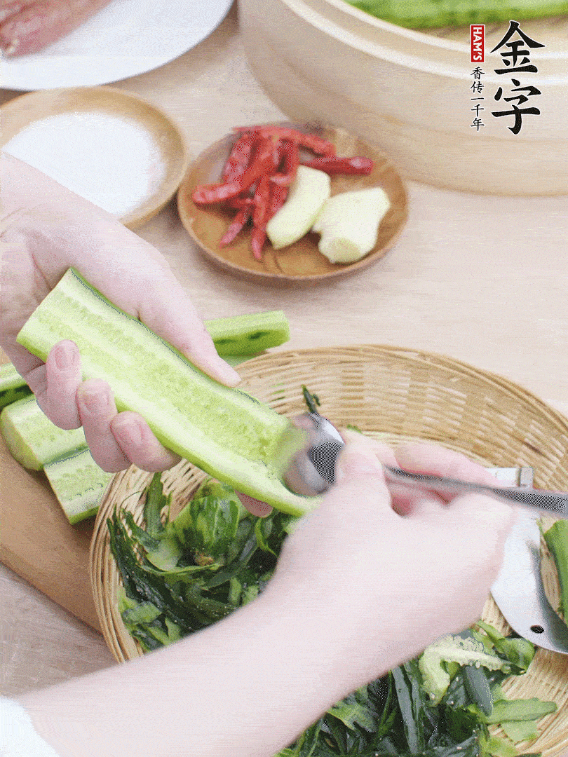 黃瓜削皮，對半切開，勺子挖去內(nèi)瓤，斜刀切片。青蒜斜刀切段。